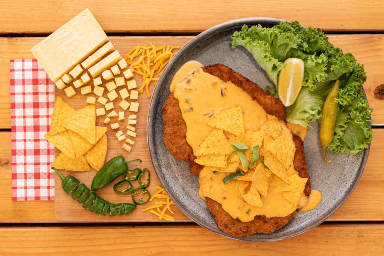 Schnitzel mit Käsesoße, Tortilla-Chips und Jalapenos